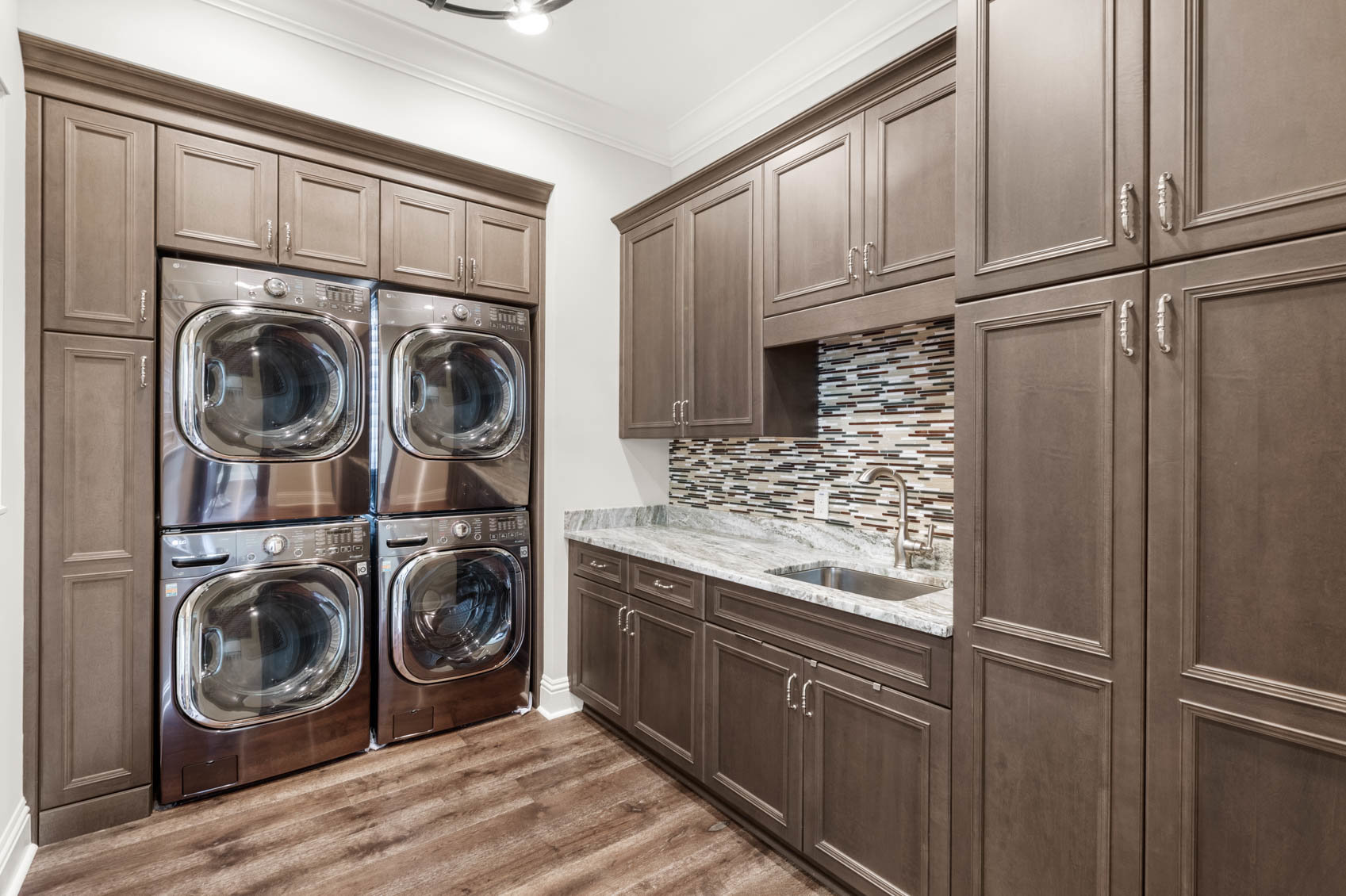 laundry room with 4 machines and brown cabinets